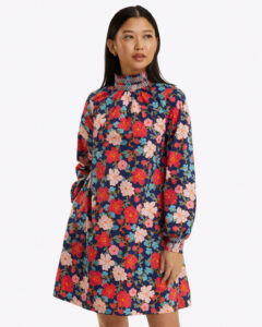 Model wearing mini length long sleeve dress with floral print in pink, red, and navy
